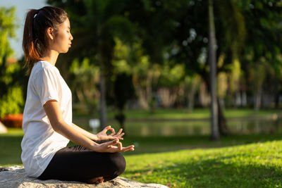 Side view of woman meditating at park