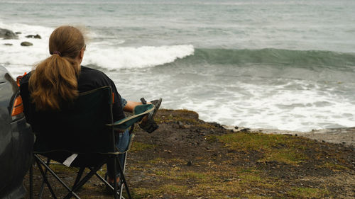 Rear view of woman sitting on beach