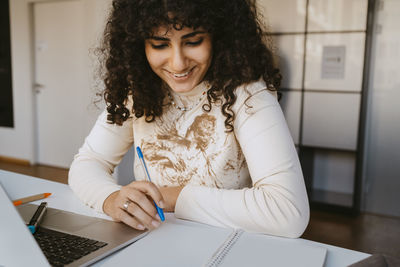 Smiling young woman with curly hair studying at community college