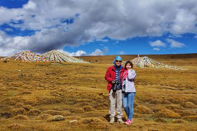 Portrait of friends standing on field against sky