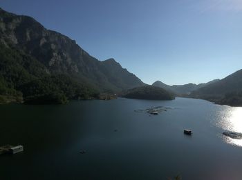 Scenic view of lake and mountains against clear blue sky