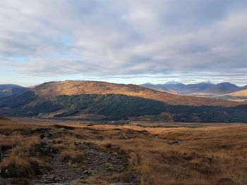 Scenic view of field and mountains against sky