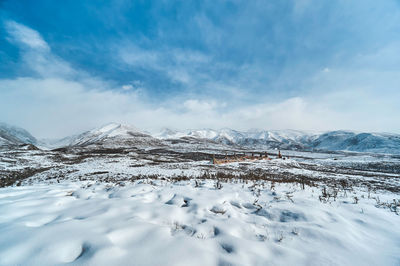 Scenic view of snow covered landscape against cloudy sky