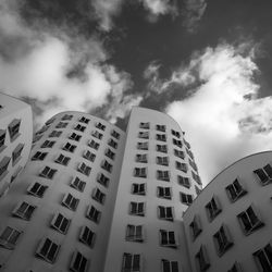 Low angle view of skyscraper against cloudy sky