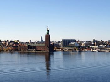 River and buildings in city against clear sky