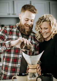 Man and woman smile as they prepare to make a coffee pour over