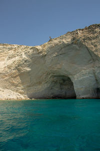 Rock formations by sea against clear blue sky