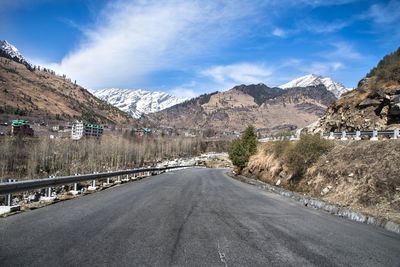 Road amidst snowcapped mountains against sky