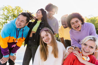 Portrait of smiling friends standing against sky