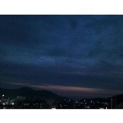 View of illuminated cityscape against cloudy sky