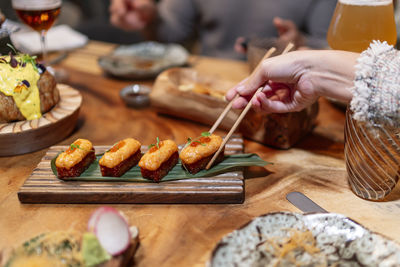 Woman hand taking food with chopsticks at restaurant