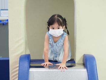 Cute girl wearing protective mask on slide