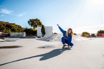 Cheerful caucasian woman with blonde hair skating in urban setting