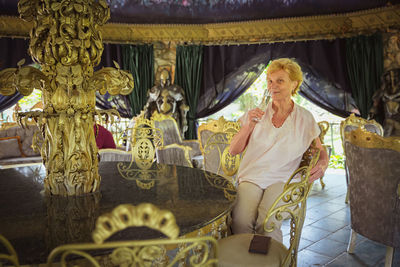 Elderly woman traveler sitting alone on the terrace of coffee shop