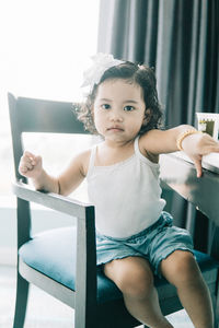 Cute girl sitting on chair at home