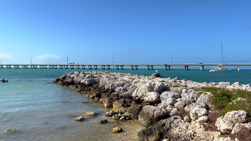 Pier over sea against clear blue sky