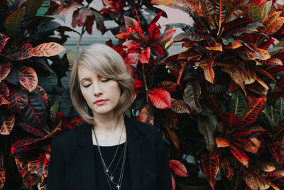 Portrait of beautiful young woman standing against plants