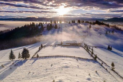 Scenic view of snow covered landscape against sky during sunset