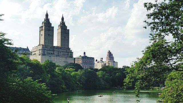 tree, architecture, building exterior, built structure, water, sky, waterfront, cloud - sky, river, reflection, growth, tower, lake, green color, city, cloud, travel destinations, day, travel, outdoors