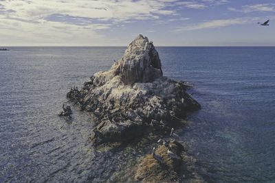 Rock formation in sea against sky