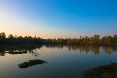 Scenic view of lake against clear sky at sunset