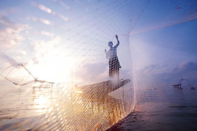 Fishing net on sea against sky during sunset