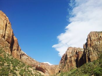 Low angle view of rocky mountain against blue sky