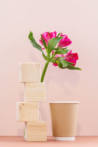 Close-up of pink flower vase on table against wall