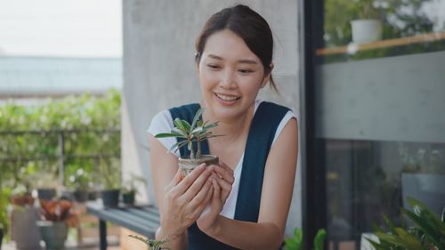 Portrait of a smiling young woman holding plant