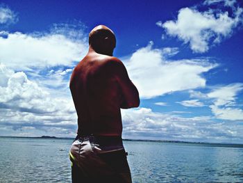 Rear view of a shirtless man overlooking sea