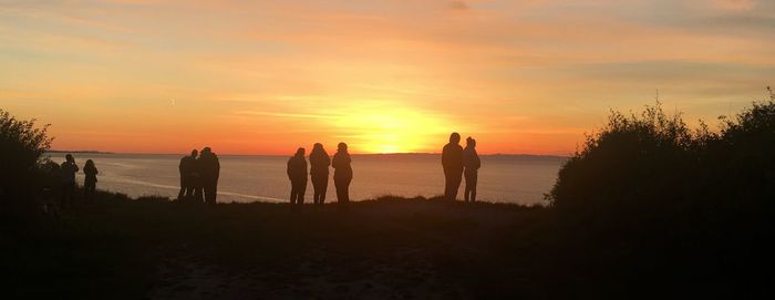 Silhouette people on beach against sky during sunset