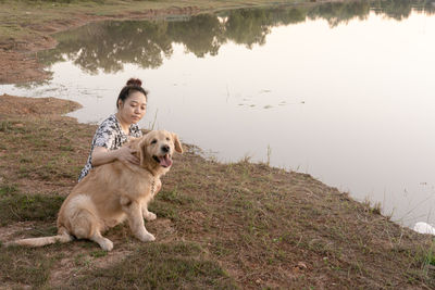 Dog sitting on land by lake