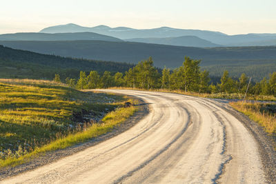 Curve on a dirt road with a scenic view of a forest landscape with the mountains on the horizon