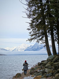 Rear view of woman standing on snowcapped mountain against sky