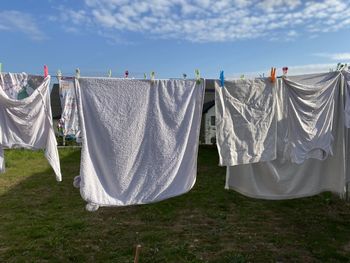 Clothes drying on clothesline on field against sky