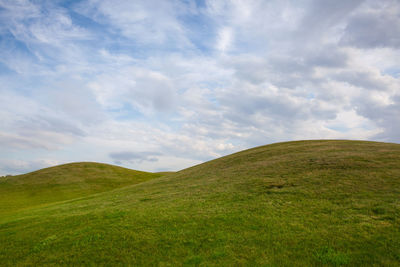 Scenic view of grassy field against sky