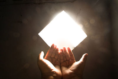 Person hand against illuminated wall