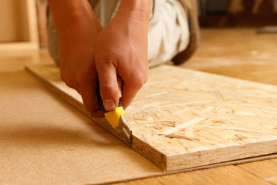 Cropped hand of woman cutting wood