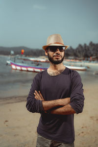 Portrait of young man wearing sunglasses standing at beach