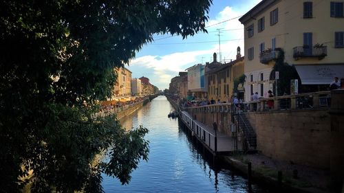Houses by river in city against sky