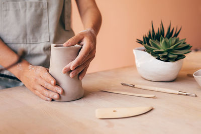 Midsection of woman making pot at table