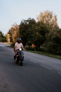 Young handsome male with hipster outfit rides a black vintage motorbike. he is a caucasian male 