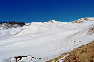 Scenic view of snowcapped mountains against clear blue sky
