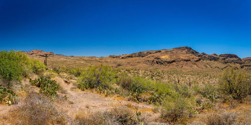 Scenic view of arid landscape against clear blue sky