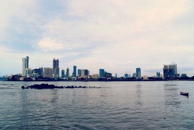 City skyline by sea against sky