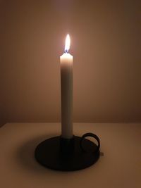 Close-up of lit candle on table in darkroom