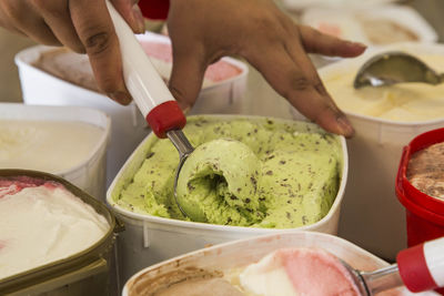Cropped image of hand scooping ice cream from container for sale
