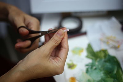 Close-up of hand cutting paper at table