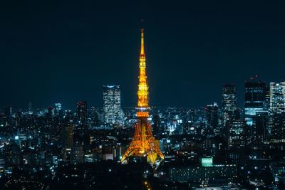 Illuminated tokyo tower amidst buildings at night