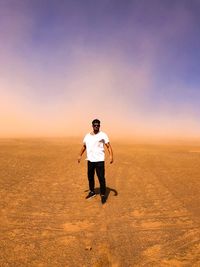 Full length portrait of man standing at desert against sky 